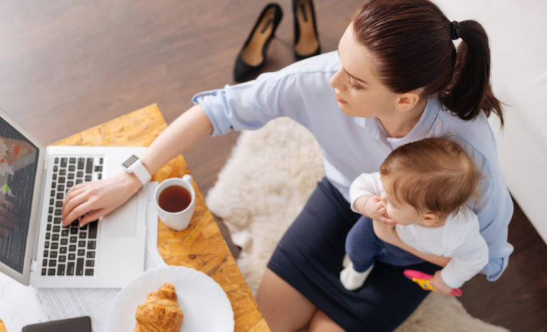 mom working at laptop holding a child